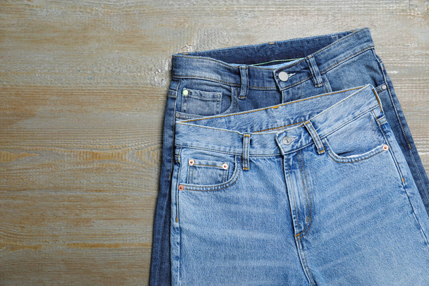 New stylish jeans on wooden background, flat lay - 写真・画像