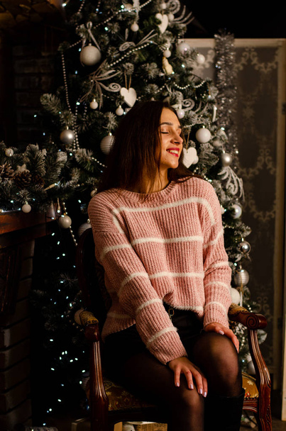 Noel ağacının arka planında hediye kutusu olan, siyah etekli, koyu kahverengi saçlı, seksi, güzel bir kız. Yılbaşı fotoğraf çekimi - Fotoğraf, Görsel