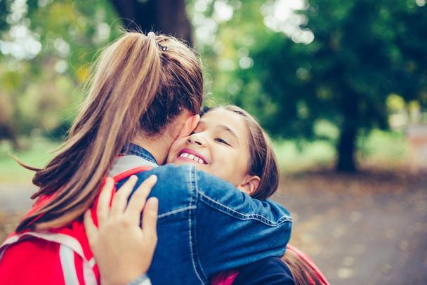 Twee gelukkige meisje knuffelen, emotionele ontmoeting in het park. - Foto, afbeelding