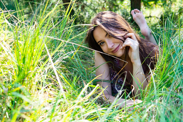 Femme aux cheveux bruns posant à la jetée en bois au lac. Femme en tenue d'été le dos tourné vers la passerelle en bois du lac Neusiedl. Réflexions du soleil au hangar à bateaux en arrière-plan. - Photo, image