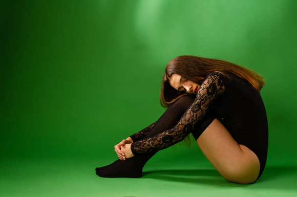 girl in black bodysuit on green background - Foto, afbeelding