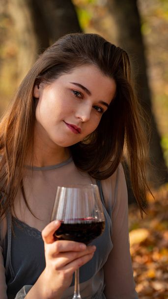 fiatal gyönyörű nő egy pohár borral a parkban ősszel - Fotó, kép