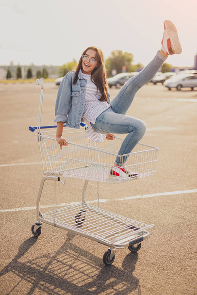 Excited young lady having fun on shopping trolley - Foto, immagini