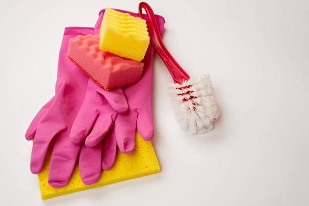 Éponge, brosse domestique, gants en latex couchés sur un dosseret blanc
 - Photo, image