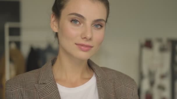 A calm pretty young businesswoman is looking to the camera indoors - Filmmaterial, Video