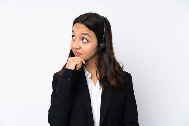 Mulher jovem telemarketer isolado em fundo branco com dúvidas e com expressão facial confusa
 - Foto, Imagem