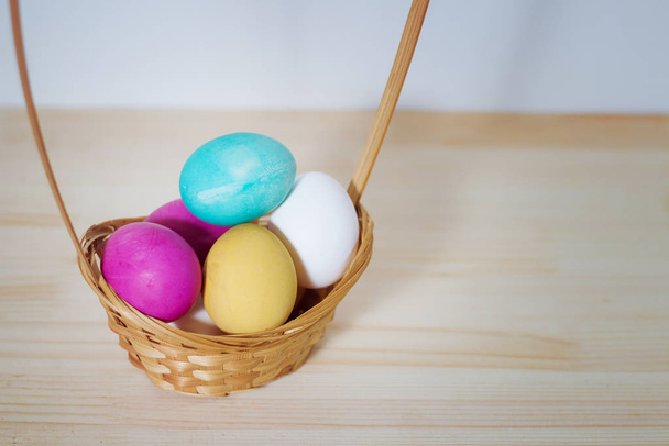 colored Easter eggs in a wooden basket on a table with space for - Valokuva, kuva