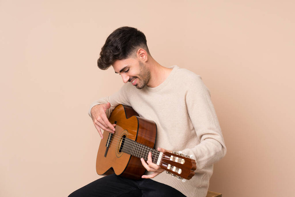 Young man with guitar over isolated background - 写真・画像