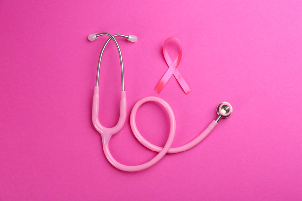 Pink ribbon as breast cancer awareness symbol and stethoscope on color background, flat lay - Fotoğraf, Görsel