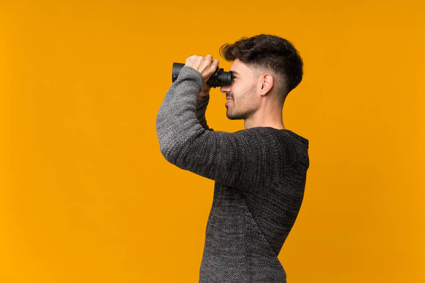Young man over isolated background with black binoculars - Zdjęcie, obraz