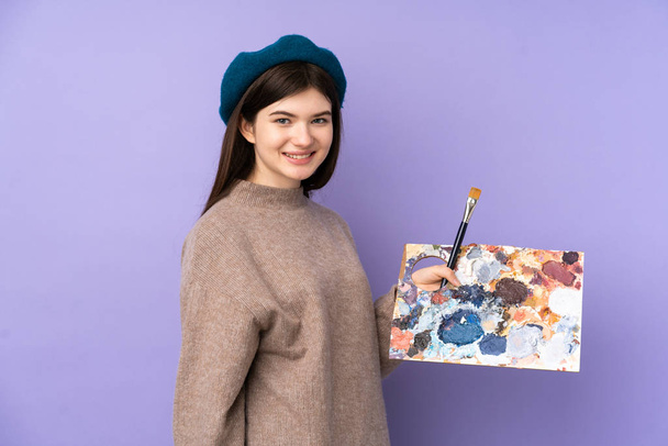 Ukrajinský Mladý umělec dívka drží paletu přes izolované fialové pozadí s úsměvem hodně - Fotografie, Obrázek