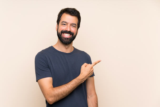 Homme à barbe pointant vers le côté pour présenter un produit
 - Photo, image
