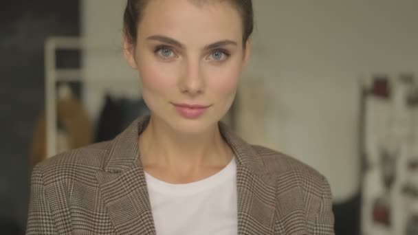 An attractive young businesswoman is looking to the camera indoors - Felvétel, videó