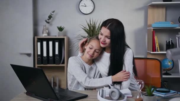 Όμορφη ευτυχισμένη μελαχρινή γυναίκα αγκαλιάζει χαμογελαστή έφηβη κόρη της και μετά κόρη φιλάει μαμάδες μάγουλο - Πλάνα, βίντεο