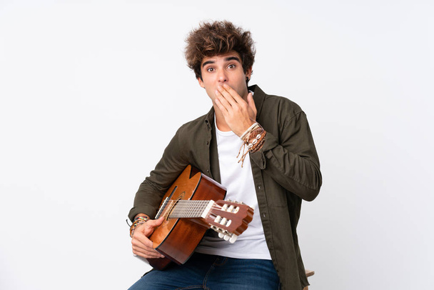 Young caucasian man with guitar over isolated white background with surprise facial expression - Фото, изображение