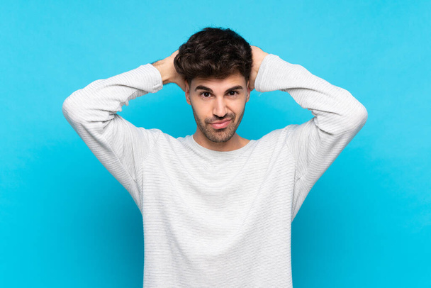 Young man over isolated blue background frustrated and takes hands on head - Foto, Bild