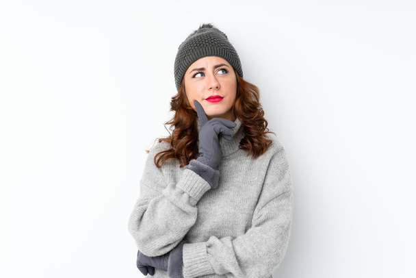 Kışlık şapkalı genç bir Rus kadın izole edilmiş beyaz arka planda bir fikir düşünüyor. - Fotoğraf, Görsel