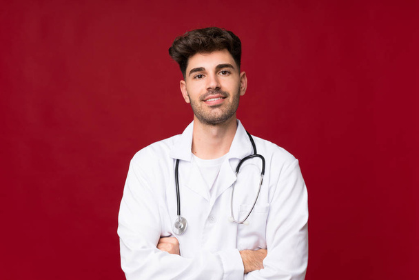 Young man over isolated background with doctor gown - Photo, Image