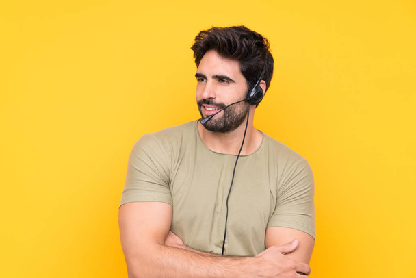 Telemarketer man working with a headset over isolated yellow background looking to the side - Foto, Imagen