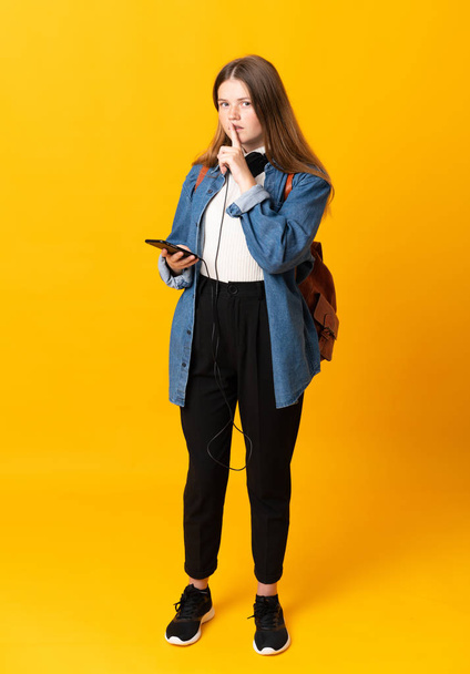 Estudiante ucraniano adolescente chica sobre aislado amarillo fondo haciendo silencio gesto
 - Foto, imagen