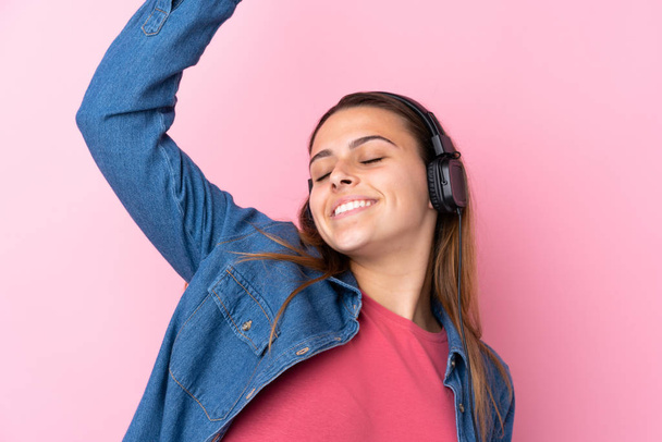 Menina adolescente ouvindo música e dançando sobre wal rosa isolado
 - Foto, Imagem