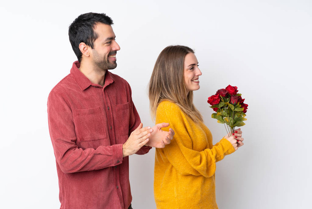Couple in Valentine Day holding flowers over isolated background applauding after presentation in a conference - Fotoğraf, Görsel