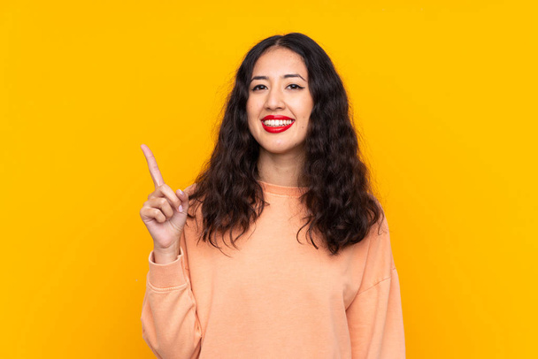 Spanish Chinese woman over isolated yellow background showing and lifting a finger in sign of the best - Fotoğraf, Görsel