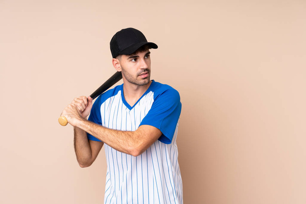 Young man over isolated background playing baseball - Valokuva, kuva