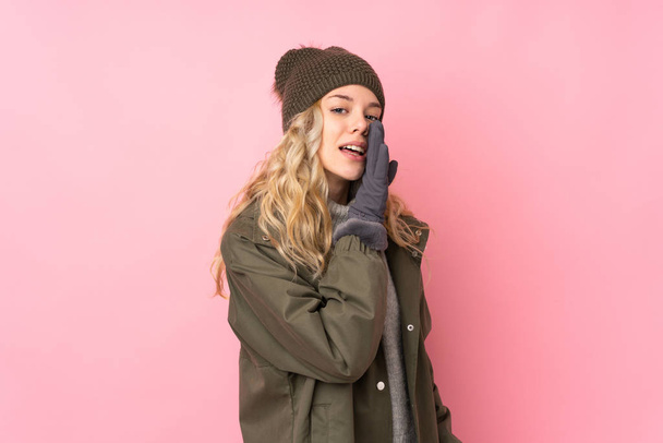 Young girl with winter hat isolated on pink background whispering something - Fotografie, Obrázek