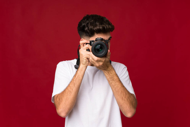 Młody mężczyzna na odizolowanym tle z profesjonalnym aparatem - Zdjęcie, obraz