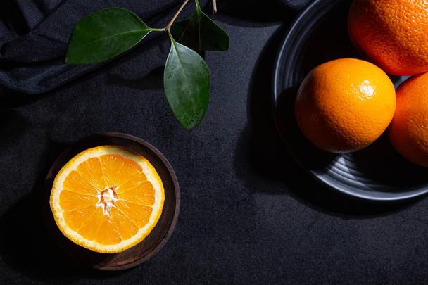 Oranges, orange slice and orange leaves on black textured background - Foto, Bild