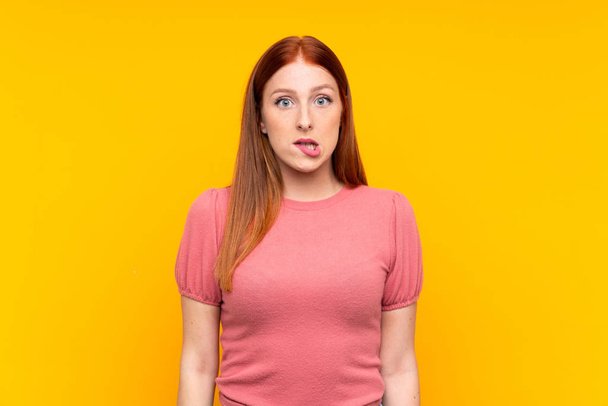 Young redhead woman over isolated yellow background having doubts and with confuse face expression - Fotó, kép