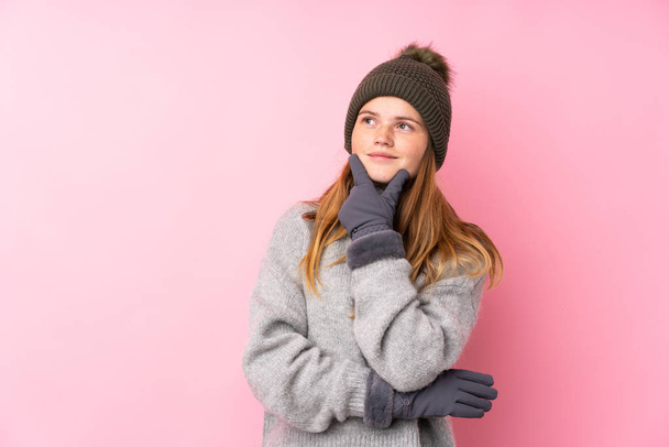 Oekraïense tiener meisje met winter hoed over geïsoleerde roze achtergrond denken een idee - Foto, afbeelding