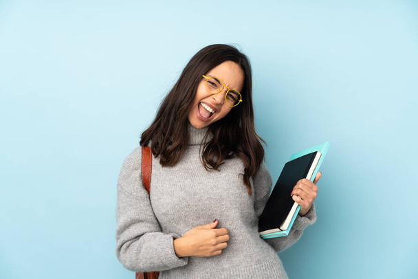 Young mixed race woman going to school isolated on blue background making guitar gesture - Photo, Image