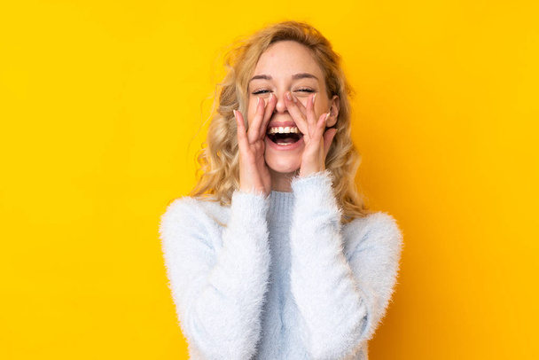Young blonde woman isolated on yellow background shouting and announcing something - Foto, immagini