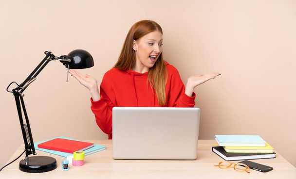 Mujer joven estudiante en un lugar de trabajo con un ordenador portátil con copyspace con dos manos
 - Foto, imagen