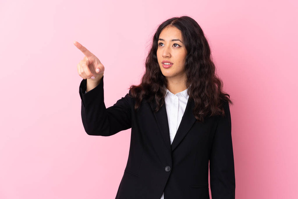 Mixed race business woman over isolated pink background touching on transparent screen - Fotó, kép