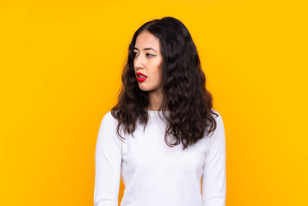 Mixed race woman over isolated yellow background looking side - Foto, imagen
