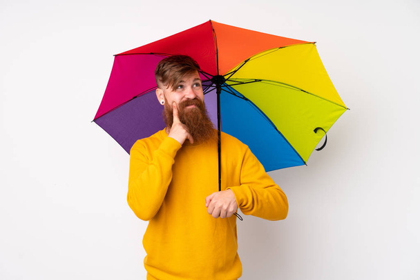ruiva homem com longa barba segurando um guarda-chuva sobre isolado fundo branco pensando uma ideia - Foto, Imagem