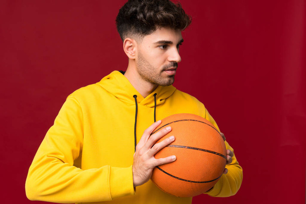 Young man over isolated background with ball of basketball - Photo, Image