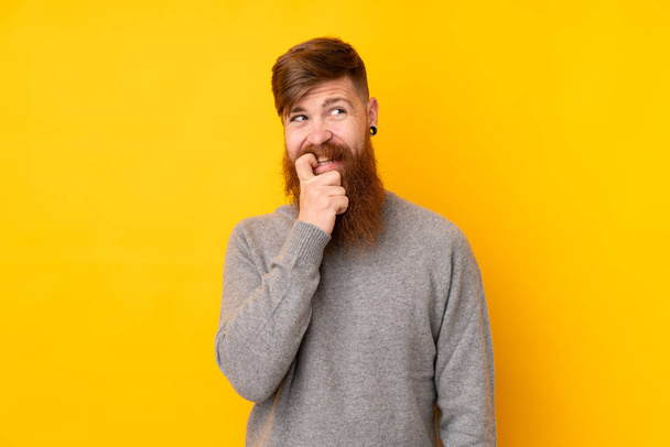 Redhead man with long beard over isolated yellow background nervous and scared - Zdjęcie, obraz