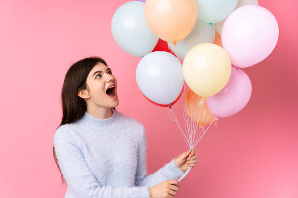 Young Ukrainian teenager girl holding lots of balloons over isolated pink background - Foto, Bild