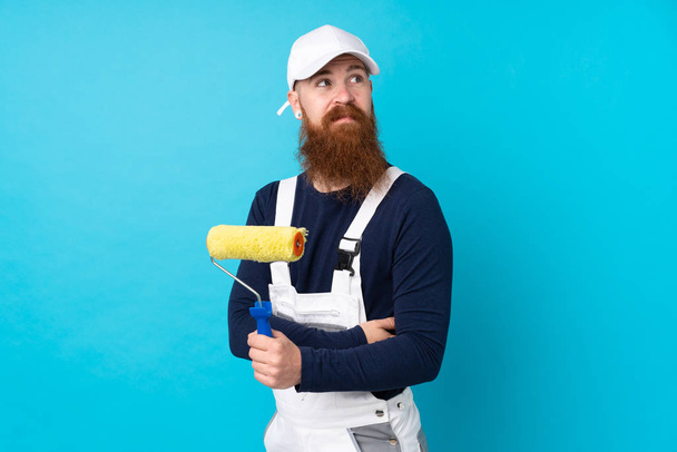 Живописець з довгою бородою над ізольованим синім фоном сміється
 - Фото, зображення