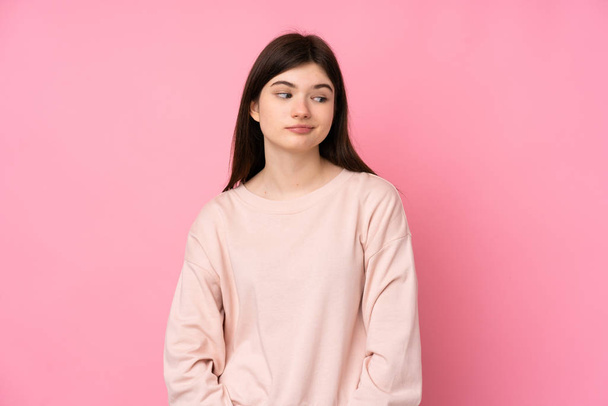 Young Ukrainian teenager girl over isolated pink background making doubts gesture looking side - 写真・画像