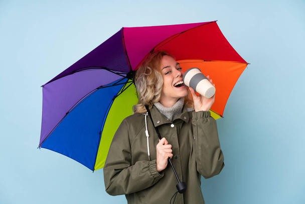 Frau mit Regenschirm isoliert auf blauem Hintergrund - Foto, Bild