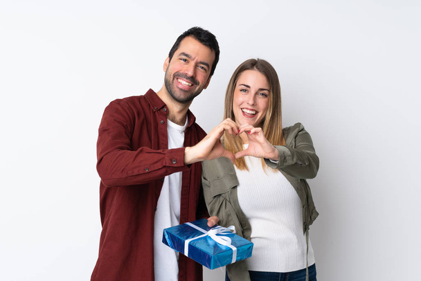 Paar in Valentijnsdag houden van een geschenk over geïsoleerde achtergrond maken van een hart met de handen - Foto, afbeelding