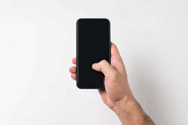 Smartphone in male hand finger on screen. White background. Blank display. Copy space - Zdjęcie, obraz