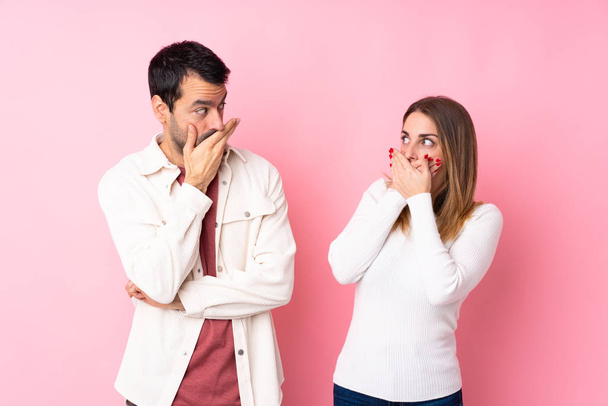 Couple in Valentine Day over isolated pink background covering mouth with hands for saying something inappropriate - Photo, image