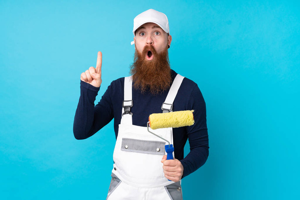 Schilder man met lange baard over geïsoleerde blauwe achtergrond met verrassing gezichtsuitdrukking - Foto, afbeelding