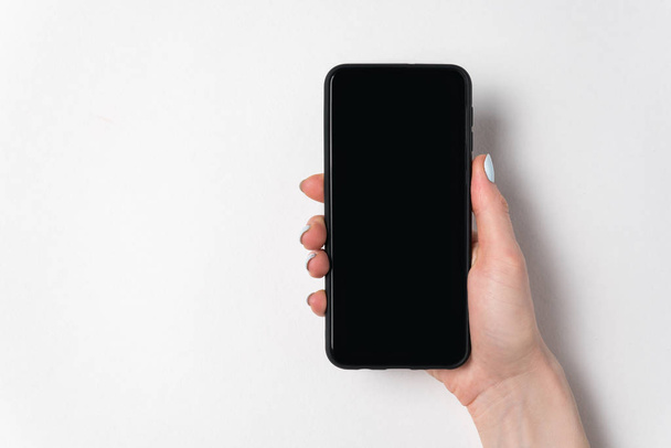 Female hand holding smartphone on white background. Blank screen. Copy space - Фото, зображення
